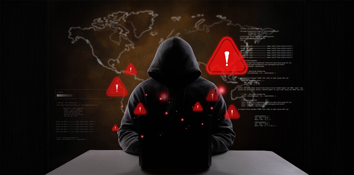 Hacker in a dark hoodie at a laptop, symbolizing cybersecurity threats and global cyberattacks.